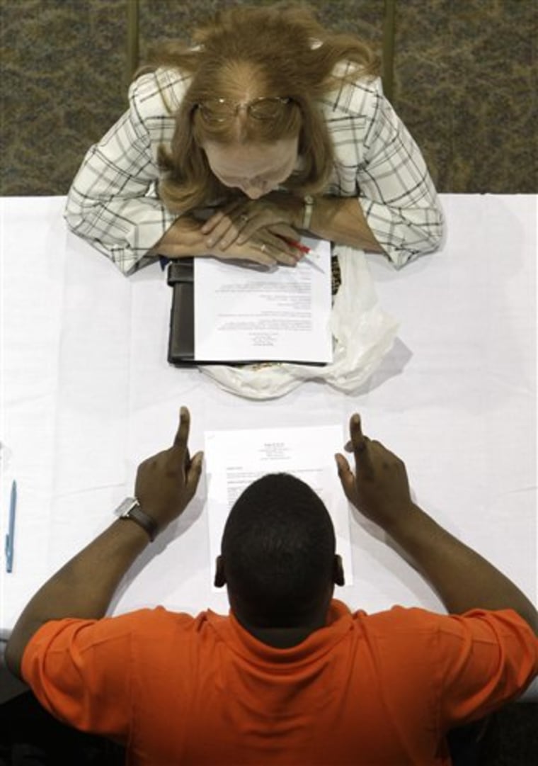 Robin Keyser, top, looks for advice on her resume while attending a job fair in Southfield, Mich.